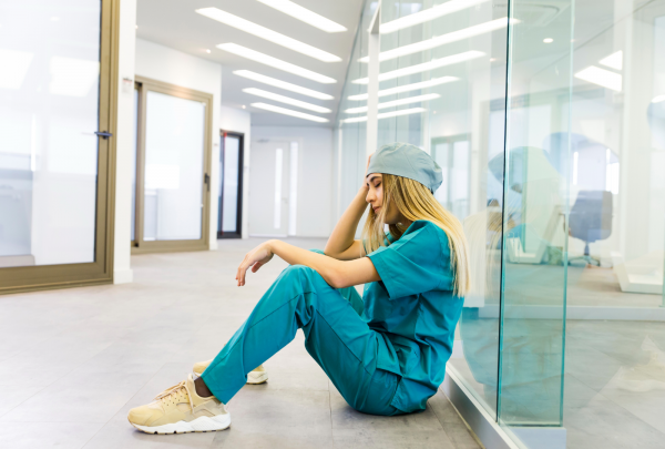 Tired nurse sitting on the floor.