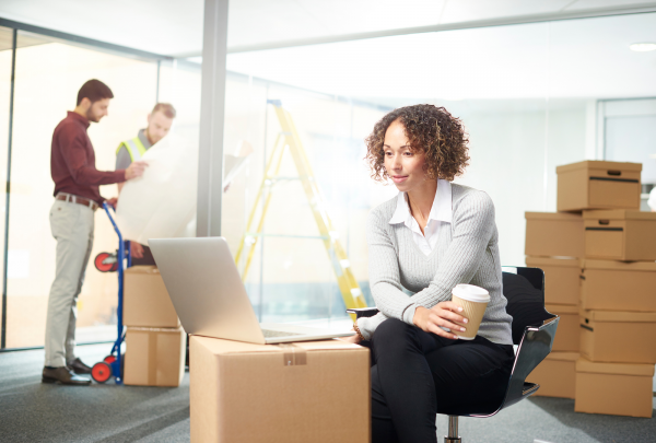 a woman sitting on a cardboard box looking at a laptop