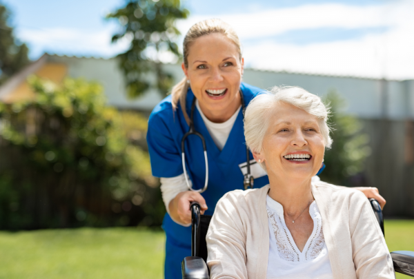 A nurse and her elderly patient smiling in the garden