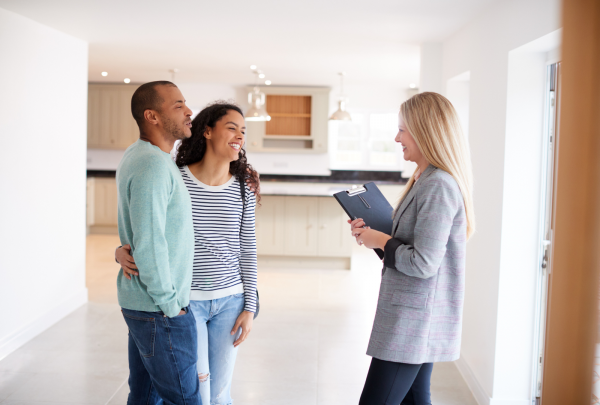 A couple smiling with a landlord about their new house